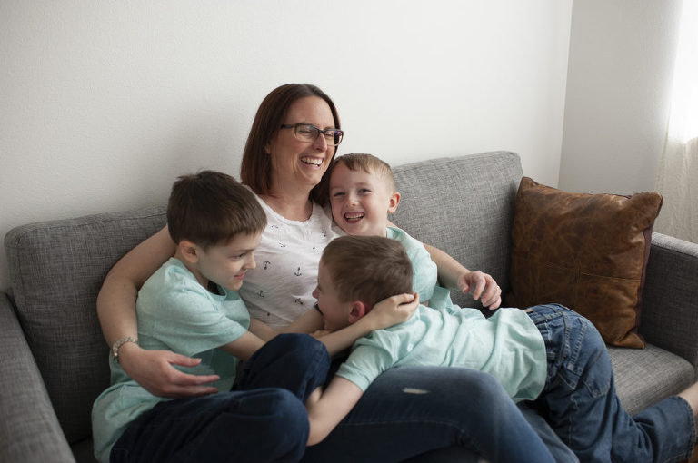 mom and her 3 boys all snuggle on the couch