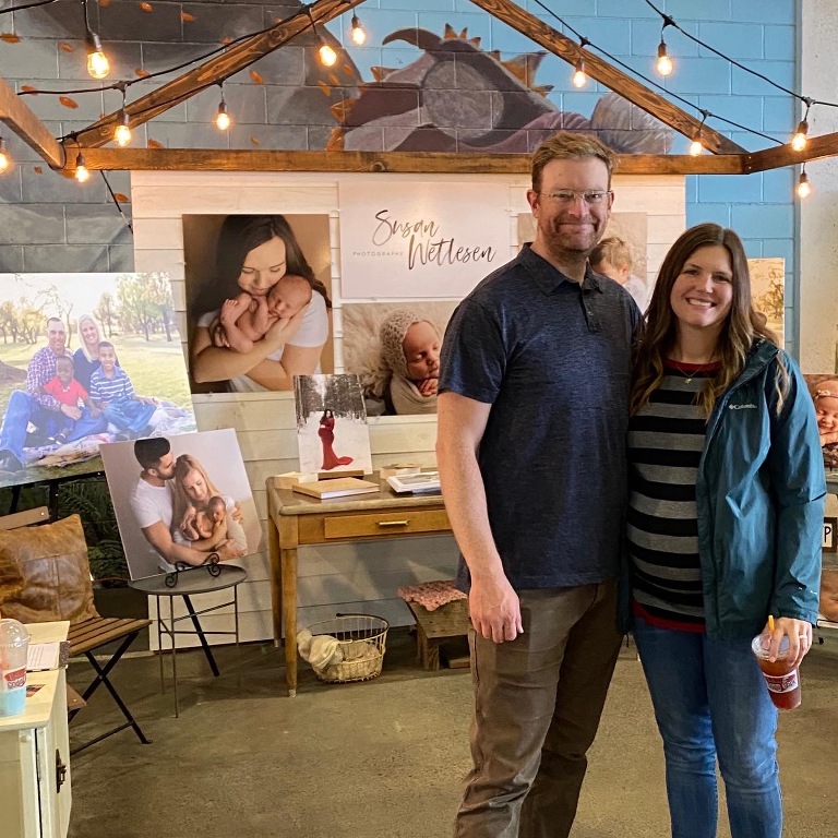 Alaskan family photographer poses at booth during open air market