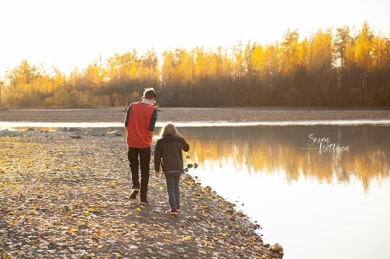 children walk along river in Alaska with layers on during family photos
