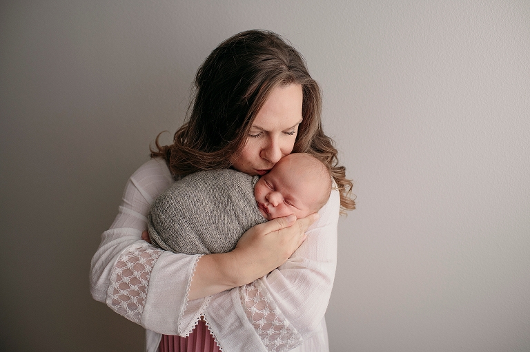 AK newborn session with mom kissing baby boy