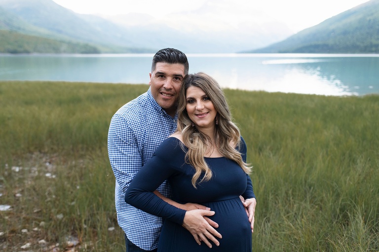 husband and wife pose during Alaska maternity session by lake
