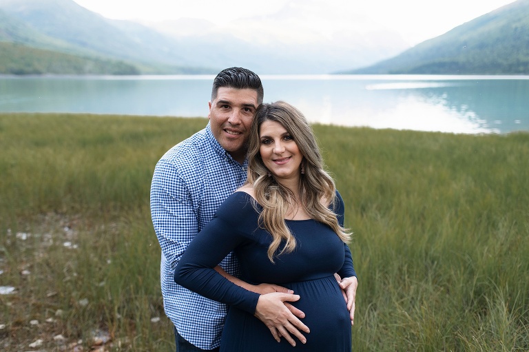 husband and wife pose during Alaska maternity session by lake