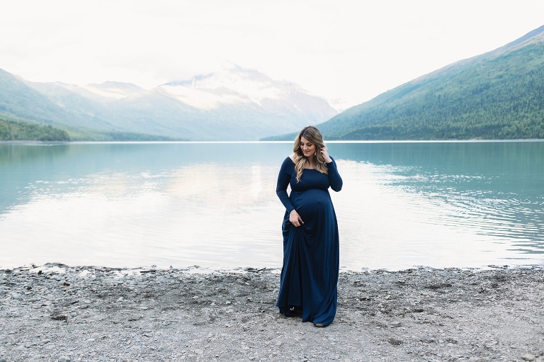 mom holds maternity dress while walking by Eklutna Lake 