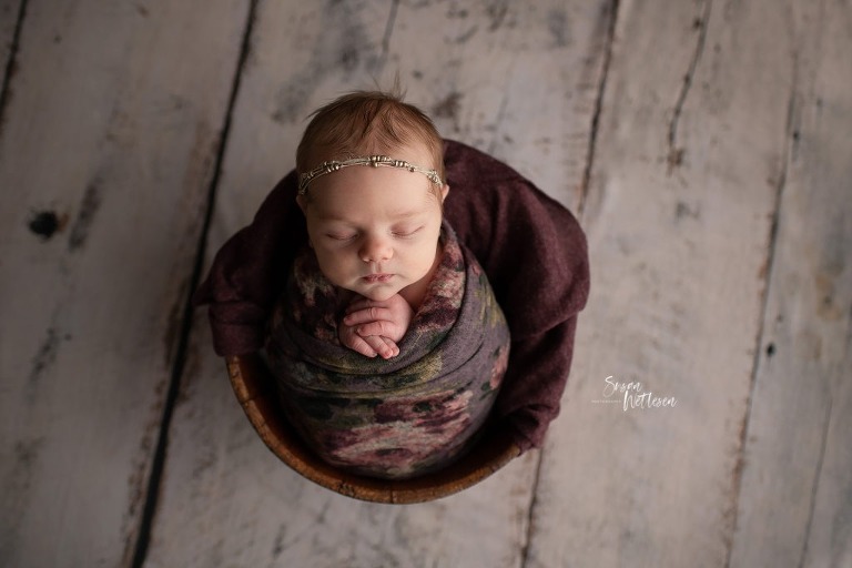 newborn in basket wrapped in floral blanket