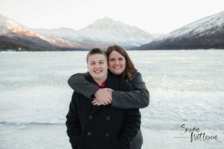 mom hugs son during Eklutna Lake winter family session