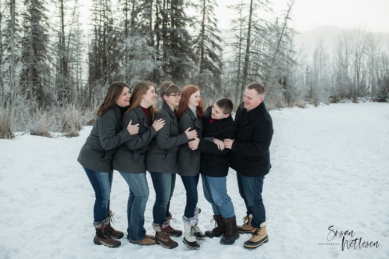 Family hugs and looks at each other during Eklutna Lake winter family session