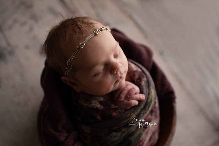 looking down on sleeping newborn wrapped in blanket with hands folded 