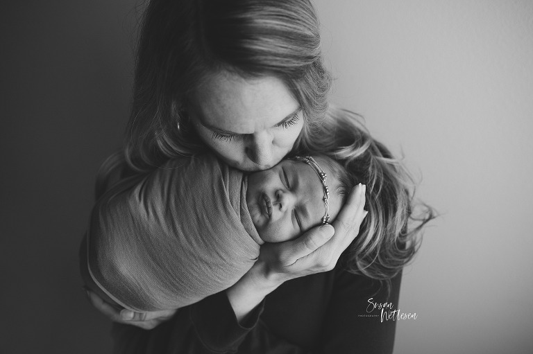mom holds baby close and kisses her cheek during Alaska Classic Newborn Portrait Session
