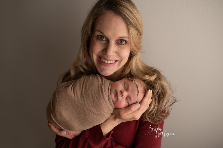 Mom holds baby up by her face and smiles during Alaska Classic Newborn Portrait Session