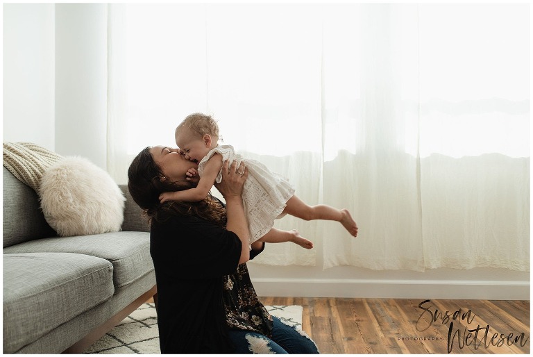 Mom lifts baby up and kisses her face during Alaska Motherhood Session