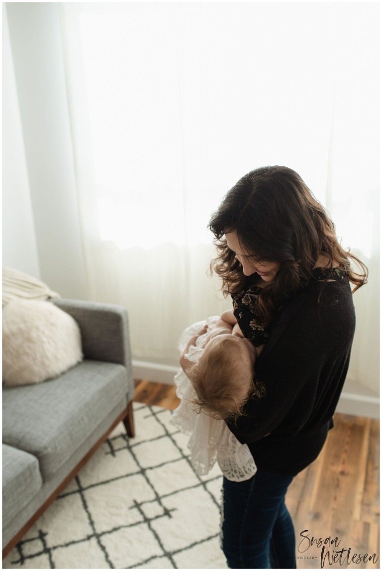 Mom holds baby girl in arms and looks down at her during Alaska Motherhood Session